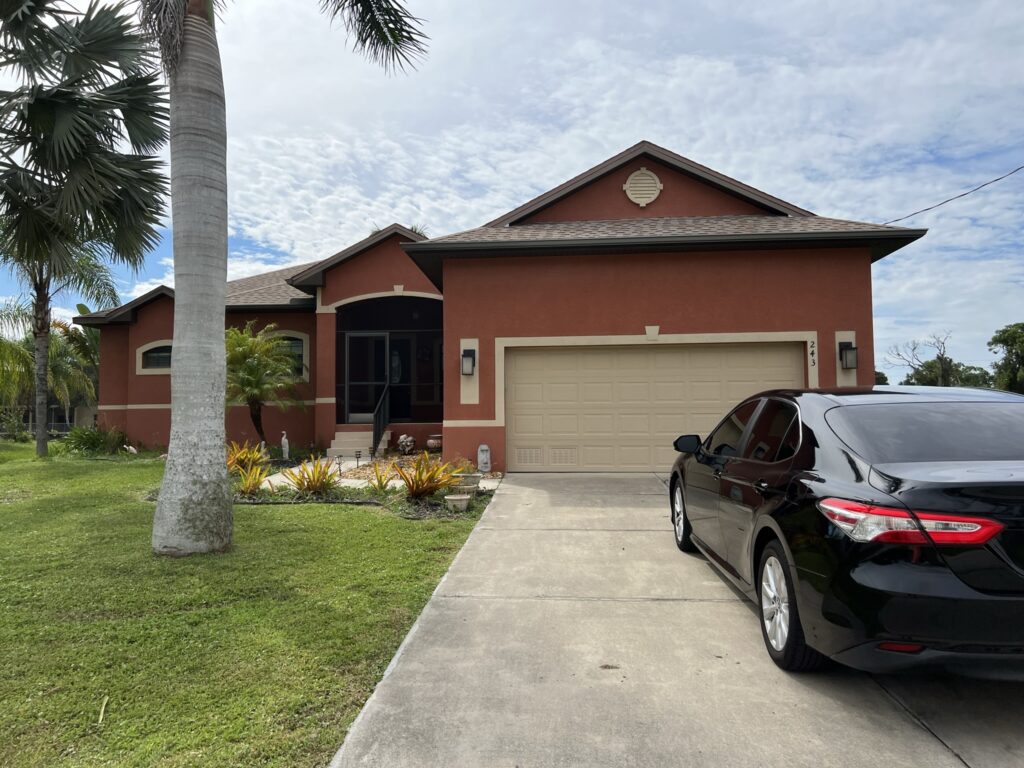 brown florida style single family house with car in driveway