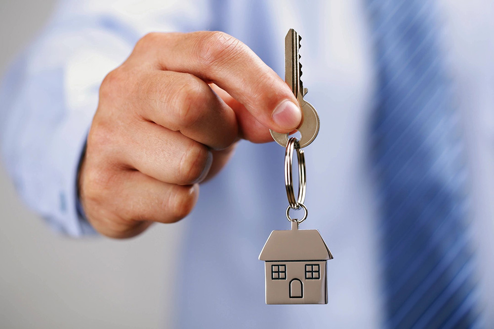 man holding key with a house-shaped keychain
